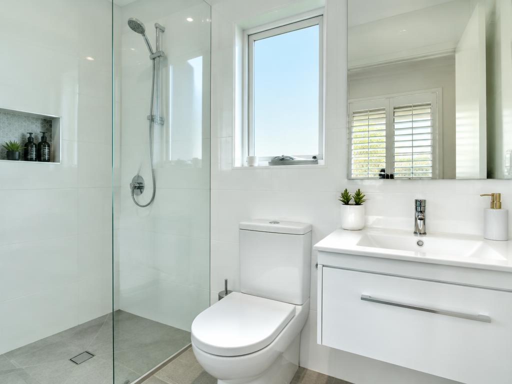 Spotless white bathroom with a gleaming glass shower screen and polished taps